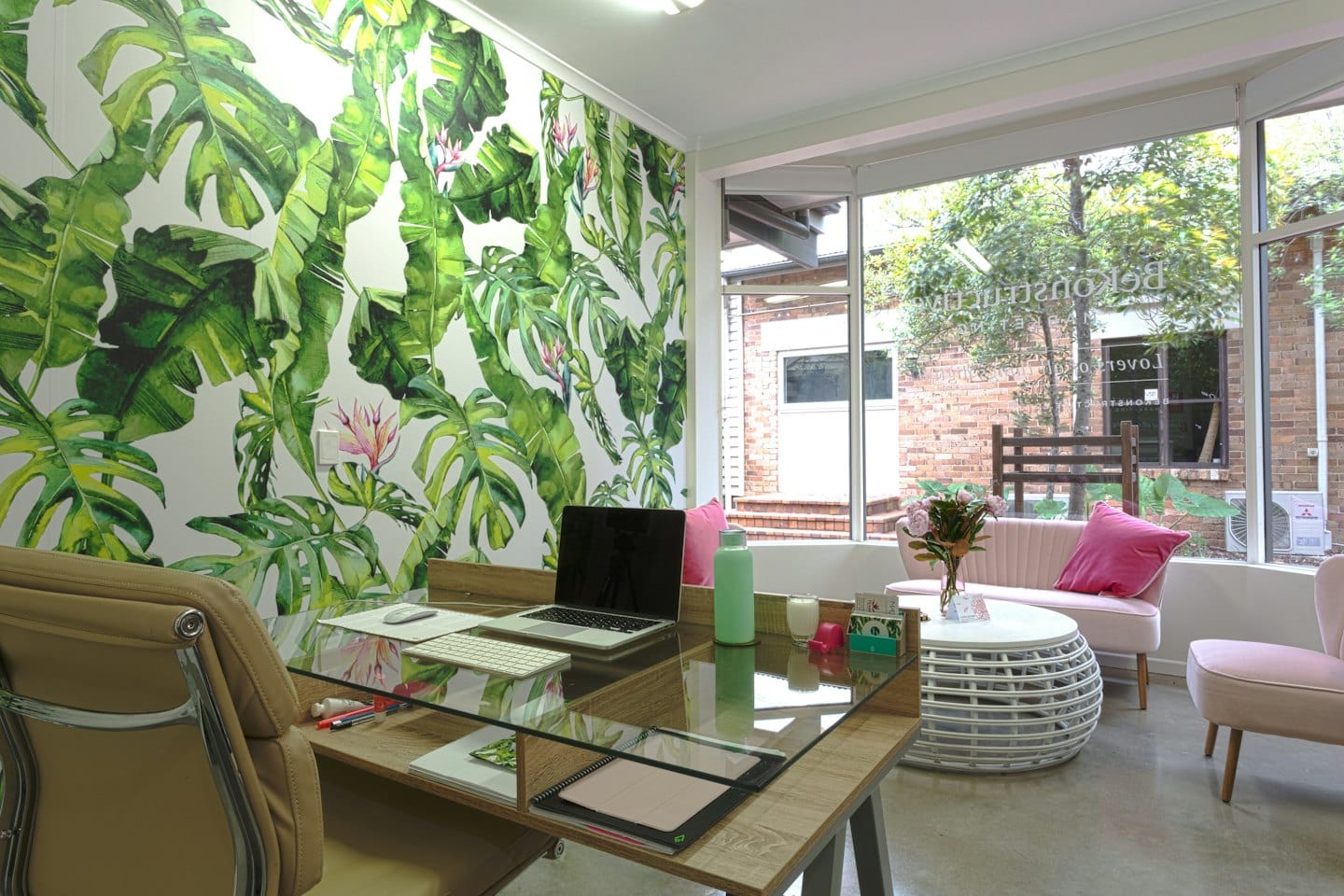 Modern office with a wooden desk and floral wall mural.